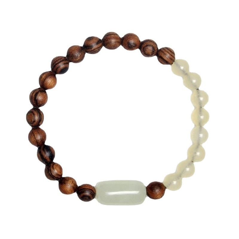 Close-up of a brown wood and pale jade beaded bracelet on a linen background