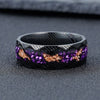 Close up view of a black textured steel ring with purple stone and gold foil inlay
