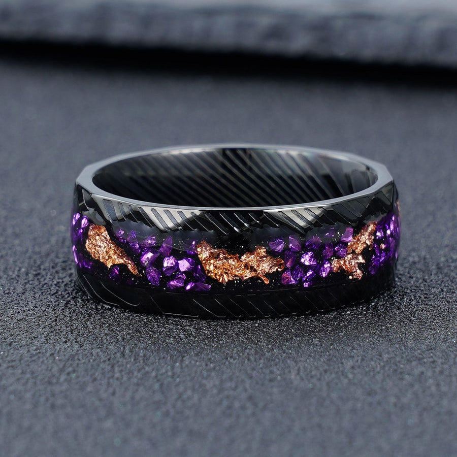 Close up view of a black textured steel ring with purple stone and gold foil inlay