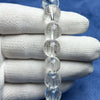 Close up of a clear glass bead bracelet held in a gloved hand showing internal engravings