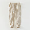 Pair of beige linen men's pants with white drawstrings and rolled cuffs