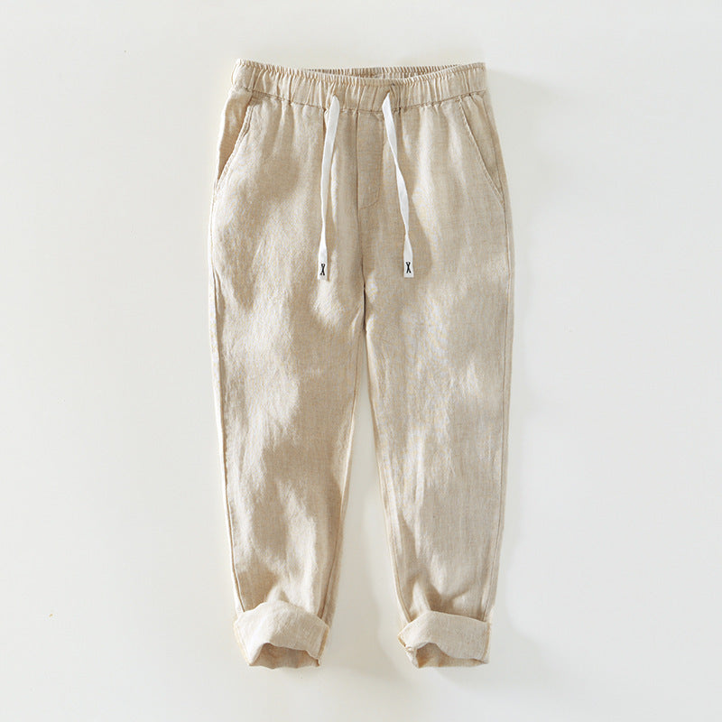 Pair of beige linen men's pants with white drawstrings and rolled cuffs
