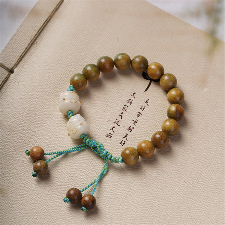 Close up of green sandalwood beads and white cat charms on a teal cord