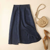 Flat lay of a navy blue cotton linen midi skirt with asymmetrical hem next to a beige bag and shoes
