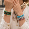 Stack of colorful geometric stone bracelets on a woman's wrist