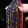 Hand holding several strands of colorful round tiger eye beads