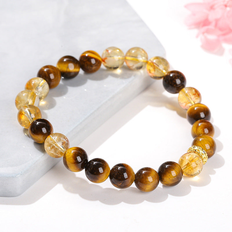 Natural tiger eye bracelet with yellow tower crystal beads and copper accent on white stone surface