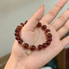 Red crystal bead bracelet with gold spacer beads and a hanging eight-pointed star charm held in hand