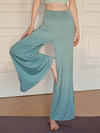 A woman wearing teal wide leg yoga pants standing on a mat