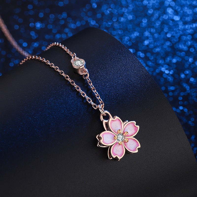 Close up of a pink cherry blossom pendant on a silver chain