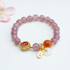 Close up of a purple beaded bracelet with an orange agate bead and gold peace buckle charm