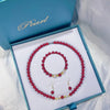 Three-piece jewelry set with red cinnabar beads and white shell beads in a blue box