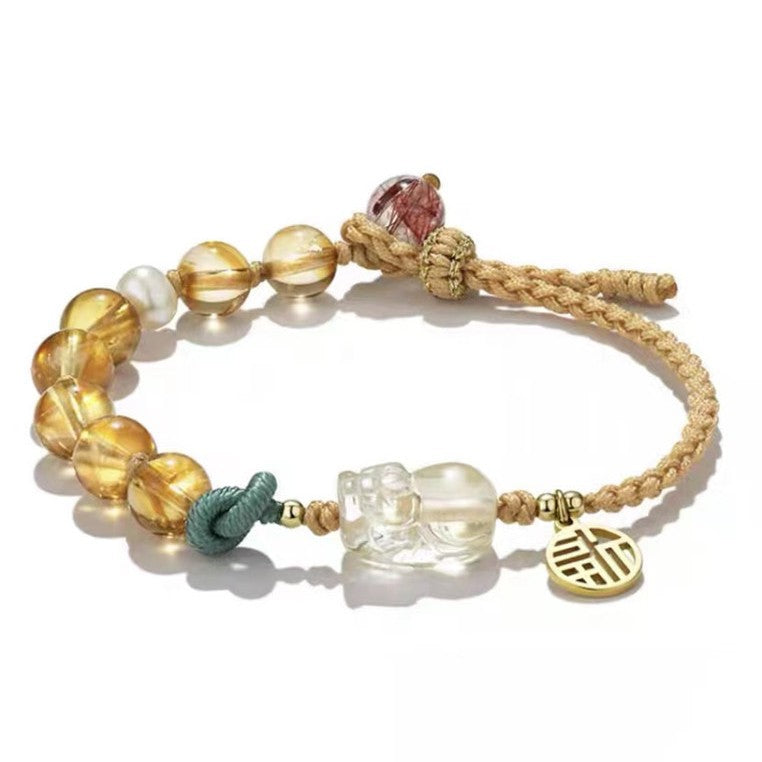 Close-up of a braided citrine bracelet with a Pixiu charm and gold Fu pendant on a white background