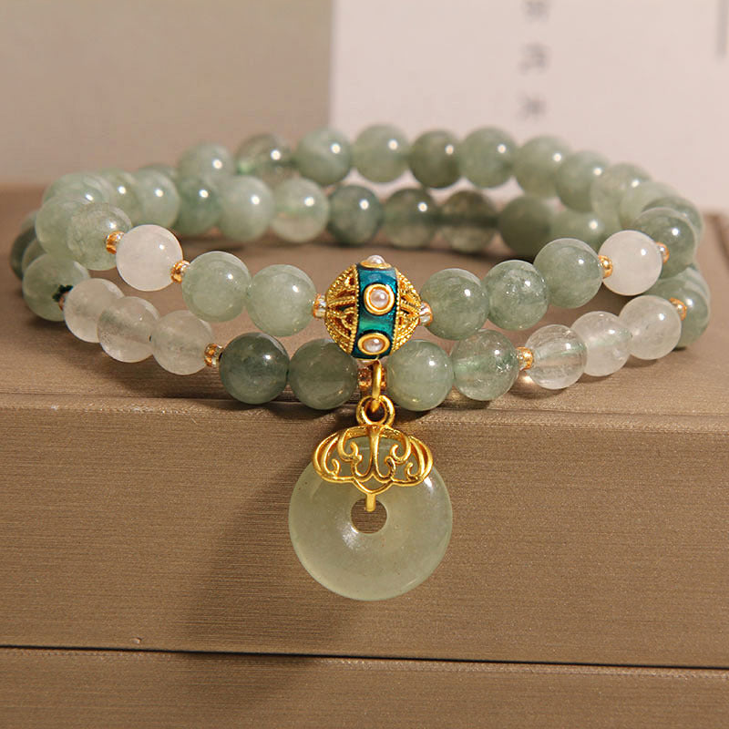 Close up of a double strand green jade and white quartz bracelet with a gold charm