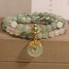 Close up of a double strand green jade and white quartz bracelet with a gold charm