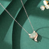 Close up of a sterling silver necklace with a light green jade fox pendant on a dark green background
