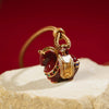 Close up of a red copper horse pendant with gold saddle on a brown cord necklace