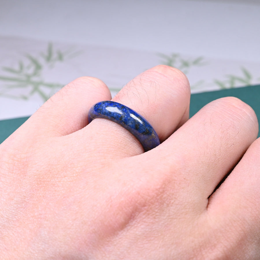 Close up view of a polished blue lapis lazuli ring on a green surface