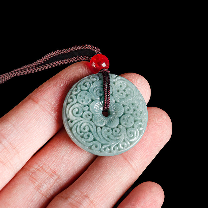 Close up of a carved green jade peace buckle pendant on a brown cord