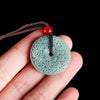 Close up of a carved green jade peace buckle pendant on a brown cord