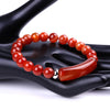 Close up of a red agate beaded bracelet with a polished curved stone bar on a black display hand.