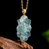 Carved natural jade lotus pendant hanging on a gold-tone chain against a dark background