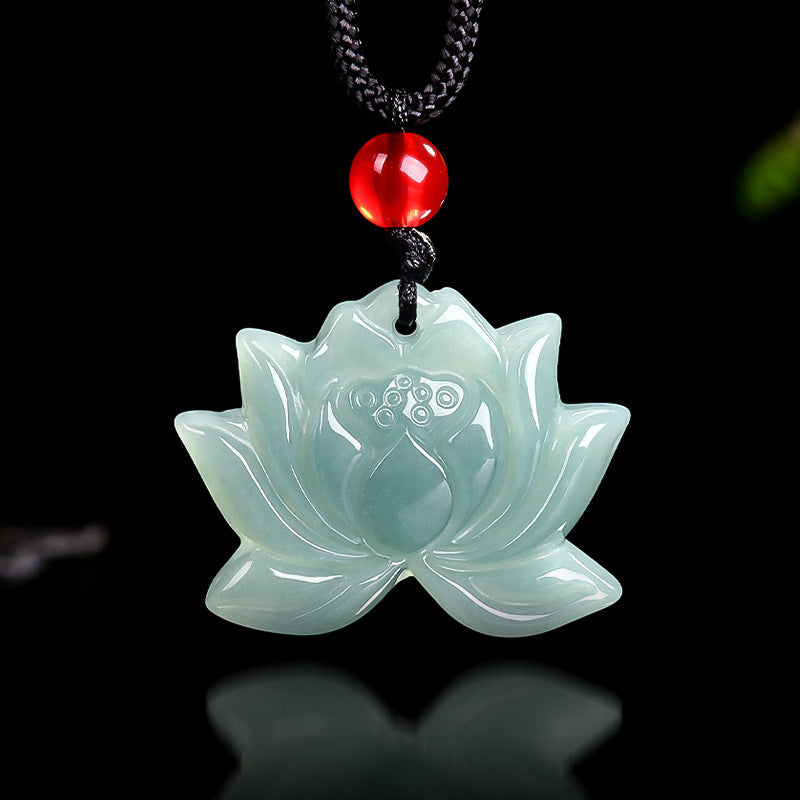 Close up of a light green carved jade lotus flower pendant on a black cord