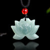 Close up of a light green carved jade lotus flower pendant on a black cord