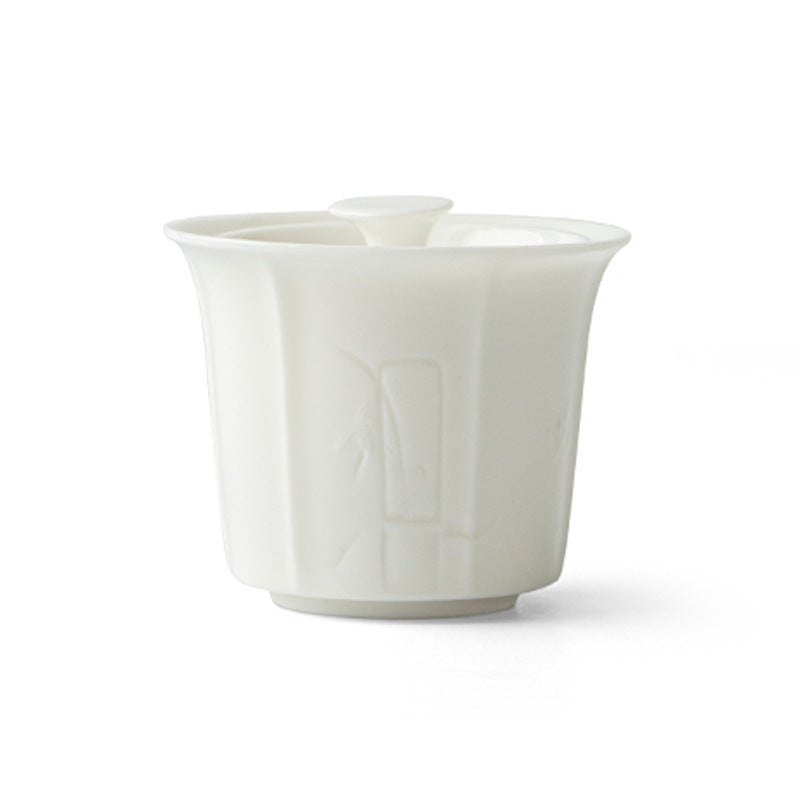 A white porcelain gaiwan teacup with a lid sitting on a wooden tray next to a small cup