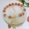 Close-up of purple amethyst beaded bracelet with gold butterfly charm on white background