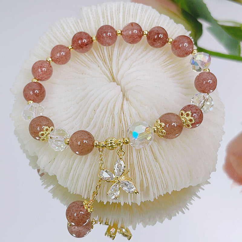 Close-up of purple amethyst beaded bracelet with gold butterfly charm on white background