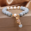 Close up of light blue crystal bracelet with pearl beads and gold money bag charm