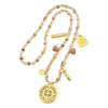 Close up of a gold tone filigree compass pendant on a strand of brown beads