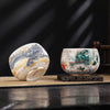 Two white ceramic tea cups with painted dragon designs sitting on a table