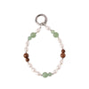 Close up of a beaded wrist strap with green stone and brown wood beads on a white background