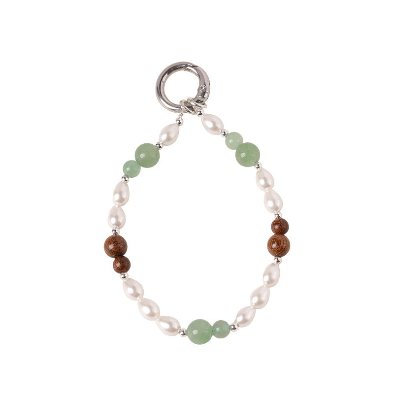 Close up of a beaded wrist strap with green stone and brown wood beads on a white background