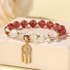 Close up of a crystal bracelet with a gold dreamcatcher charm and tassel