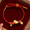 Close up of a red braided cord bracelet with a gold tone horse charm and bell