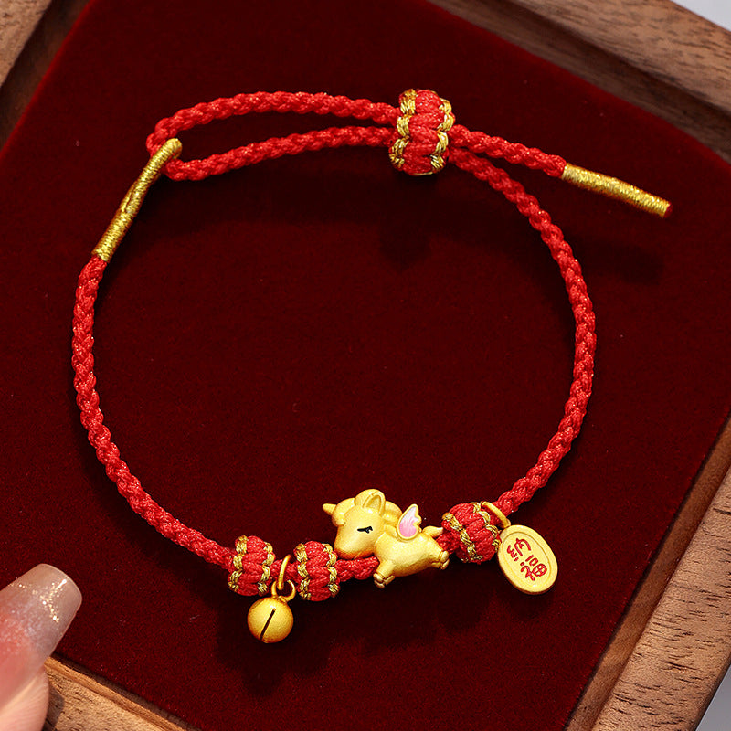 Close up of a red braided cord bracelet with a gold tone horse charm and bell