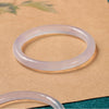 Close up of a translucent white and purple chalcedony bangle on blue fabric
