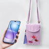 Light purple crossbody bag with red spider lily embroidery and tassel next to a smartphone