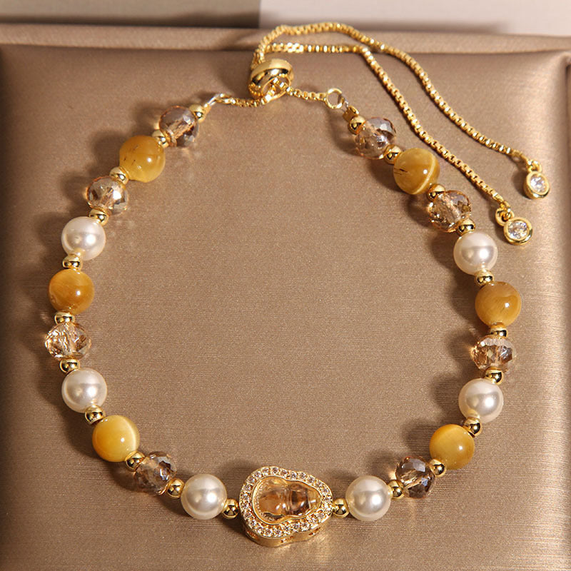 Close up of yellow tiger eye and crystal bracelet with a gourd charm