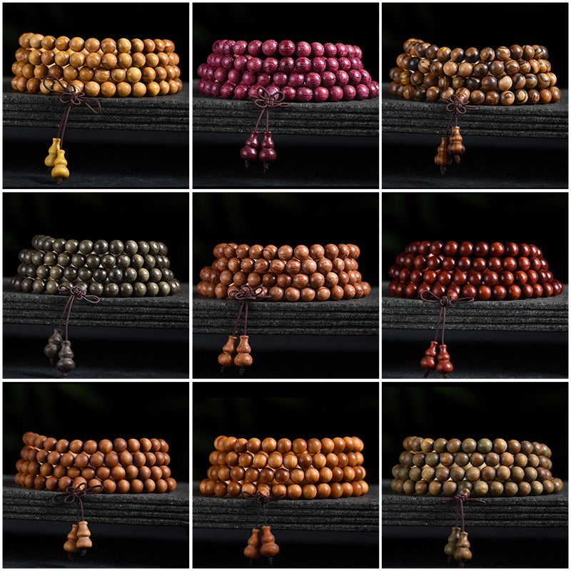 A close-up view of several wooden mala bracelets with gourd charms arranged on a dark surface.