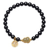 Close up of a bracelet with black beads, a jade gourd charm and a gold double happiness pendant on a wrist