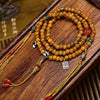 Golden brown bone bead mala with Dzi accents and tassels on a wooden surface
