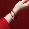 Close up of a red glass bangle with a flower charm on a wrist