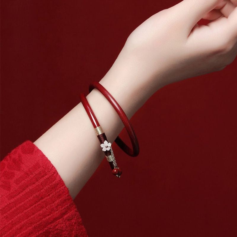 Close up of a red glass bangle with a flower charm on a wrist