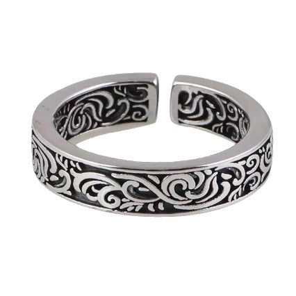 Close up view of a silver tone adjustable copper ring with black floral scrollwork pattern