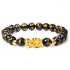 Gold-tone Pixiu charm on a black beaded bracelet with golden inscriptions