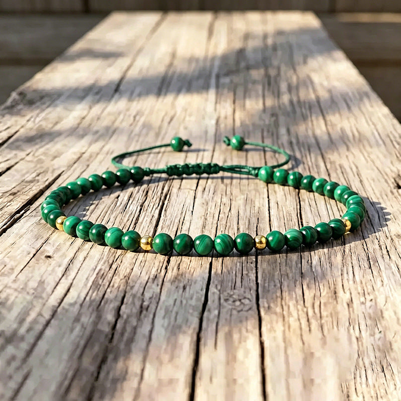 Green natural malachite bead bracelet with gold spacers on wood